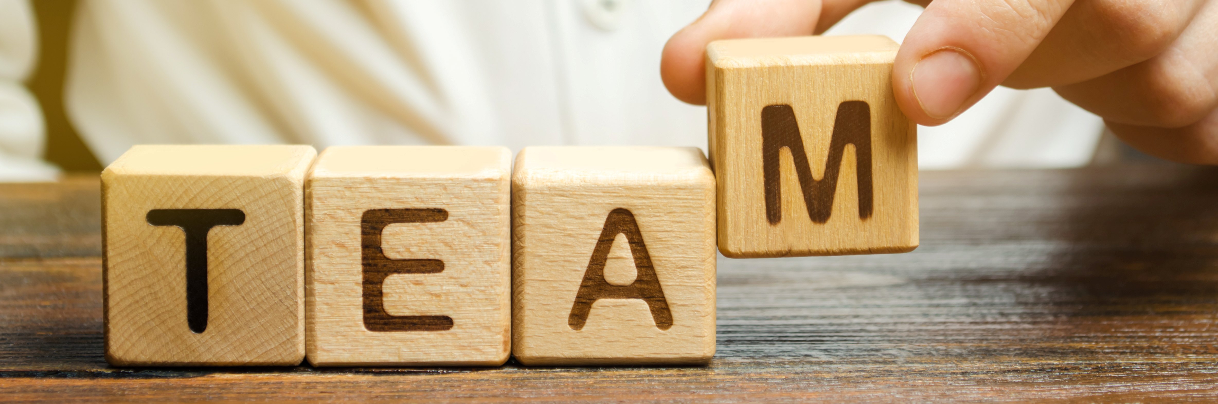 four wooden blocks that each have a letter to spell out TEAM