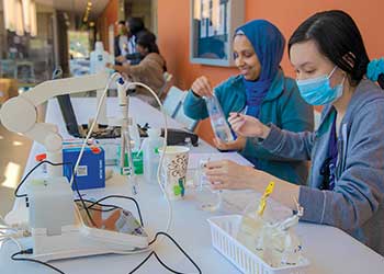 Students conduct environmental science laboratory work using testing equipment, sample containers, and measurement tools. Working at a lab bench, students analyze environmental samples and collect data to support research, sustainability, and scientific investigation.