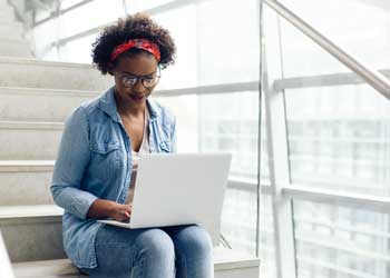 student sitting on stairs with laptop in lap