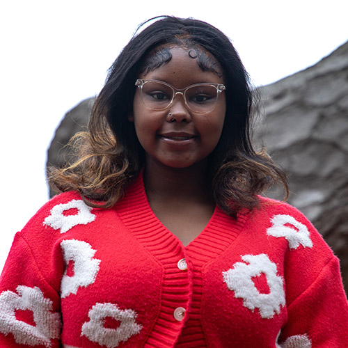 image of JyNiya Rainey wearing a red cardigan with white flowers stitched into