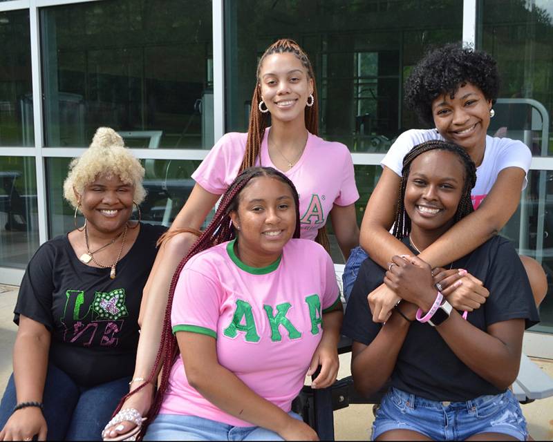 AKA group picture of five members, wearing different variations of AKA t-shirts