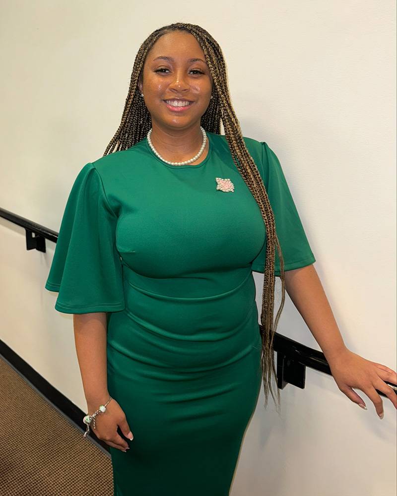 Sigma Sigma Chapter of Alpha Kappa Alpha President Alani Atkinson in a green dress with white pearls